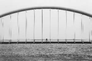 Lone Cyclist Crossing a Bridge